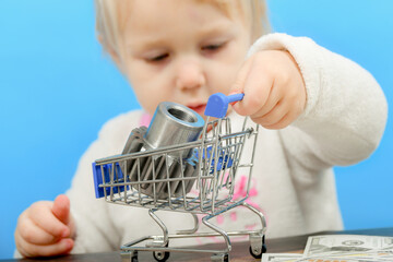 A cogwheel lies in a shopping cart and a child carries it on dollar bills. The concept of...