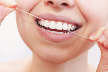 A cropped shot of a young beautiful woman flossing her teeth on a white background. Close-up. Dental concept