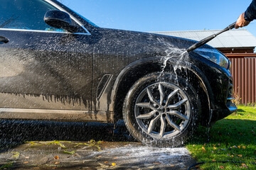 A man washes the dirt off the car with a pressure washer.