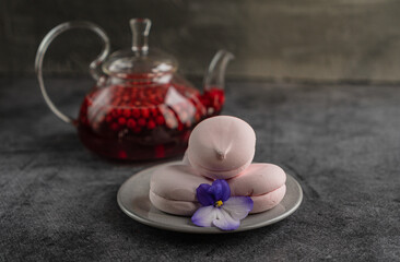 glass teapot with lingonberry drink on the table with fruit marshmallows