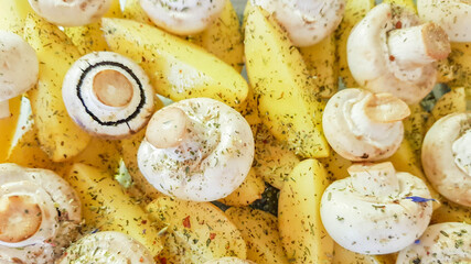 Slices of potatoes and whole champignons with spices and herbs