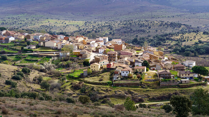 Obraz premium Aerial view of old town in the valley surrounded by mountains and green plants. Paredes Buitrago Madrid.