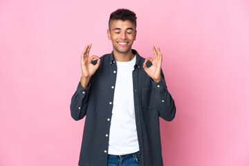 Young Brazilian man isolated on pink background in zen pose