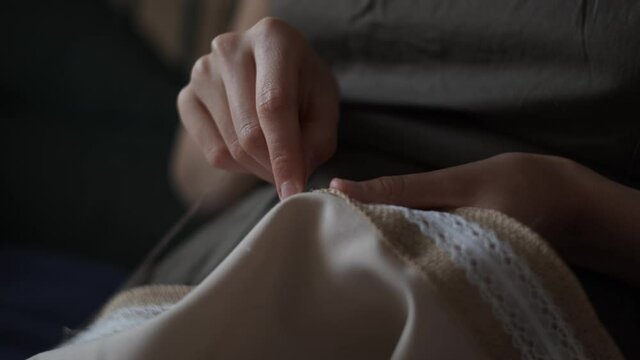 4K Closeup view of female hands sewing  jute linen stripe to beige cotton cloth. Boho rustic  style. Young woman sew tablecloth. Manual sewing.Handmade concept. Daylight. Hobby time.