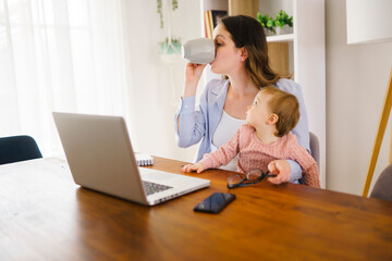 mother in kitchen home office with computer and her daugher