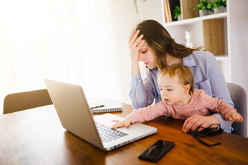 sad and frustrated mother in kitchen home office with computer and her daugher