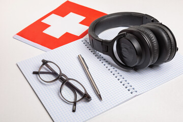 Learning foreign languages in Switzerland with audio recordings and headphones. Notepad, glasses, pen.