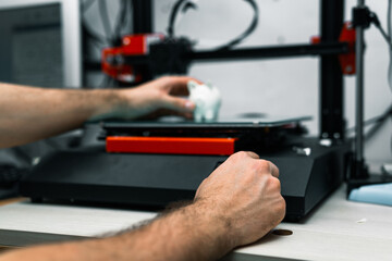 Young engineer adjusting 3D printer to print resin figures. Three-dimensional technology