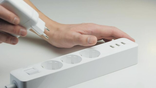 Close-up of a man's hands connecting a white power supply to a modern mains filter.