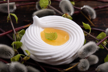 White meringue cookie with yellow lemon cream in the middle decorated with a branch from a willow tree isolated on white. Easter theme