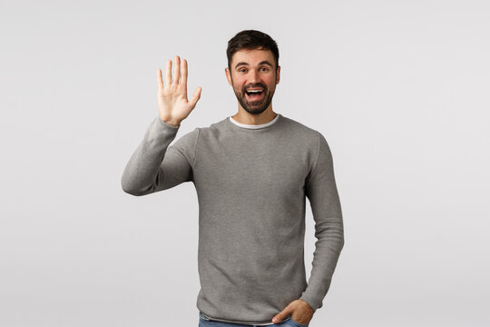 Friendly, Cheerful And Outgoing Smiling Bearded Caucasian Man, Greeting Neighbour Raising Arm And Waving In Hello, Hi Gesture, See Person As Waiting In Meeting Spot, Standing White Background