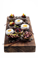 Selection of different sweet cupcakes, cookies and filled chocolate eggs on wooden board