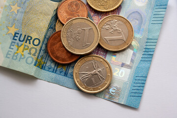 European currency. Pile of euro coins of different value on top of a partial blue euro banknote. Economy and financial concept.