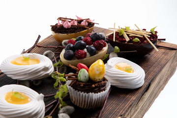 Selection of different sweet cupcakes, cookies and filled chocolate eggs on wooden board