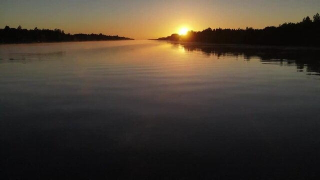Cinematic aerial view of foggy river at sunset