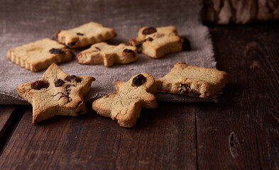 Healthy homemade gluten-free, lactose-free cookies of various shapes without sugar with raisins and chocolate on a dark brown wooden background