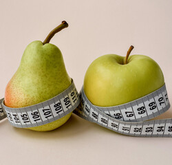 Fruit and a measuring tape on a light beige background. Close-up. Concept for a healthy and balanced diet.