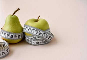 Composition with measuring tape, pear and apple on a light background. Place for your text.