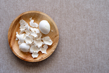 Boiled egg and eggshell in wooden bowl over rustic background with copy space.