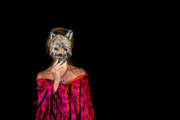 woman in purple dress and blue eyes holding a feline mask covering her face