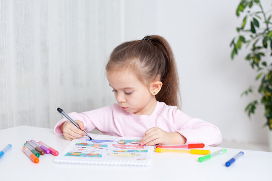 A little girl of 4-5 years diligently draws in the album color markers. classes with children at home and in kindergarten. Education of pre-school children.