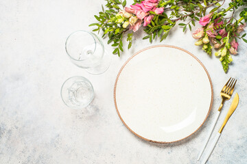Table setting with white plate, cutlery and flowers.