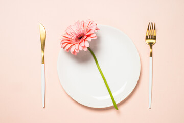 Table setting with white plate, cutlery and flowers.