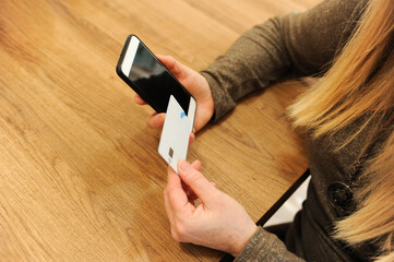 Blonde woman filling out credit card information on her mobile phone. Online shopping concept.