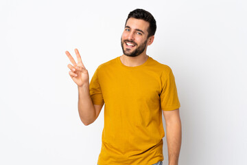 Young handsome man with beard isolated on white background smiling and showing victory sign