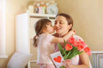 Obraz na płótnie Canvas Happy Mother's Day. The child daughter congratulates her mother and gives her a homemade card and flowers pink tulips