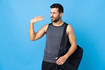 Fototapeta premium Young sport man with sport bag isolated on blue background with tired and sick expression