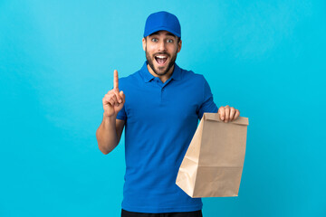 Delivery man with beard isolated on blue background pointing up a great idea