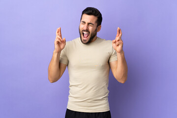 Fototapeta premium Young handsome man with beard over isolated background with fingers crossing