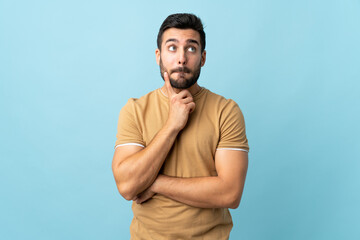 Young handsome man with beard over isolated background having doubts and thinking