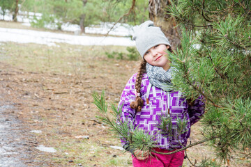 Fototapeta na wymiar In the autumn, a beautiful girl stands near a pine tree in the forest.