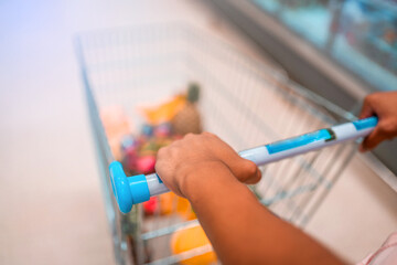 man's hand holds the shopping cart from the supermarket with blurred background