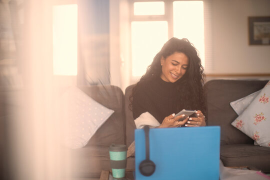 Happy woman working from home with smart phone and laptop
