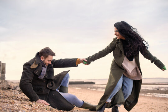 Playful couple in winter coats on beach