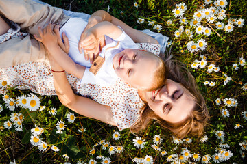 Mother and son are playing in a green meadow. 