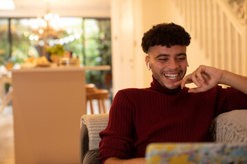 Happy young man with earbud headphones watching movie on laptop