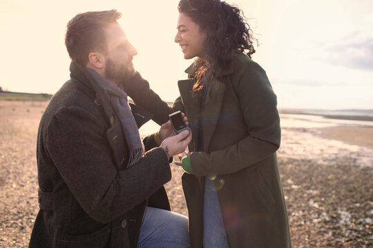 Boyfriend with wedding ring proposing to girlfriend on winter beach