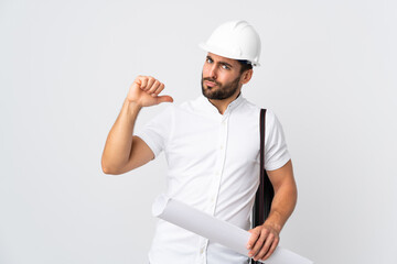 Young architect man with helmet and holding blueprints isolated on white background proud and self-satisfied