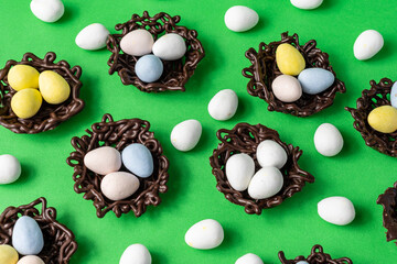 small Easter eggs in chocolate nests on a green background decoration