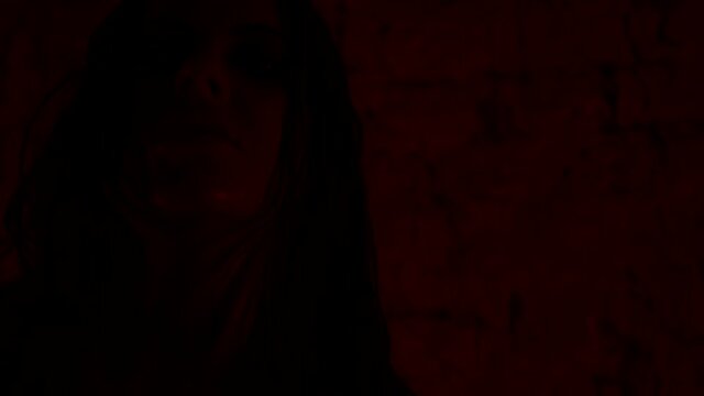 Porter girl demon bloody face dancing in neon light at halloween party