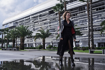 Obraz premium portrait of fashion model girl in black clothes walks on a city road with palm trees