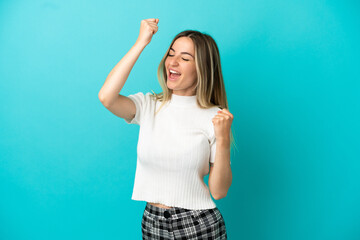 Fototapeta na wymiar Young woman over isolated blue background celebrating a victory