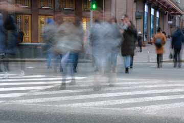 Daytime movement of people at a crosswalk in a big city. Conceptual blur image of people crossing the street in the city