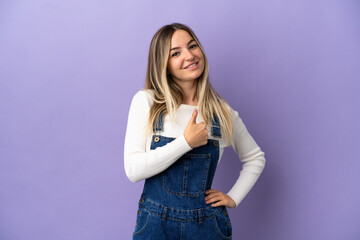 Young woman over isolated purple background giving a thumbs up gesture