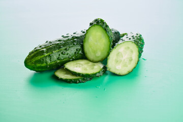 Set of fresh whole and sliced cucumbers on a green background with water drops. Garden cucumber...