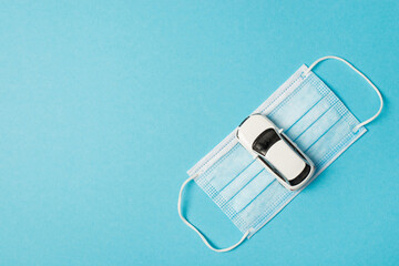 Top view photo of car model on medical face mask on isolated pastel blue background with copyspace